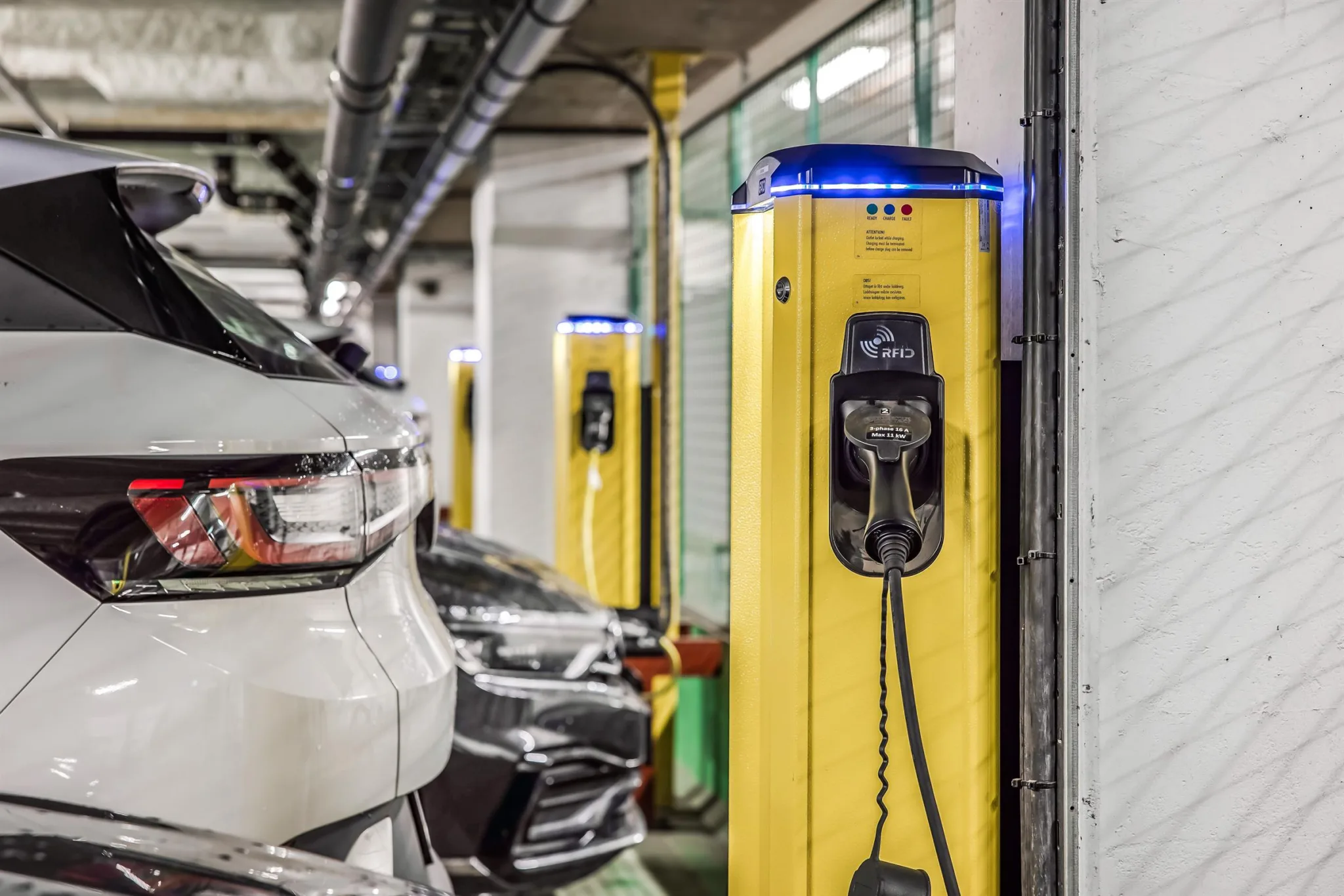 3. En parkeringsplats med gula laddstationer för elbilar och parkerade fordon.