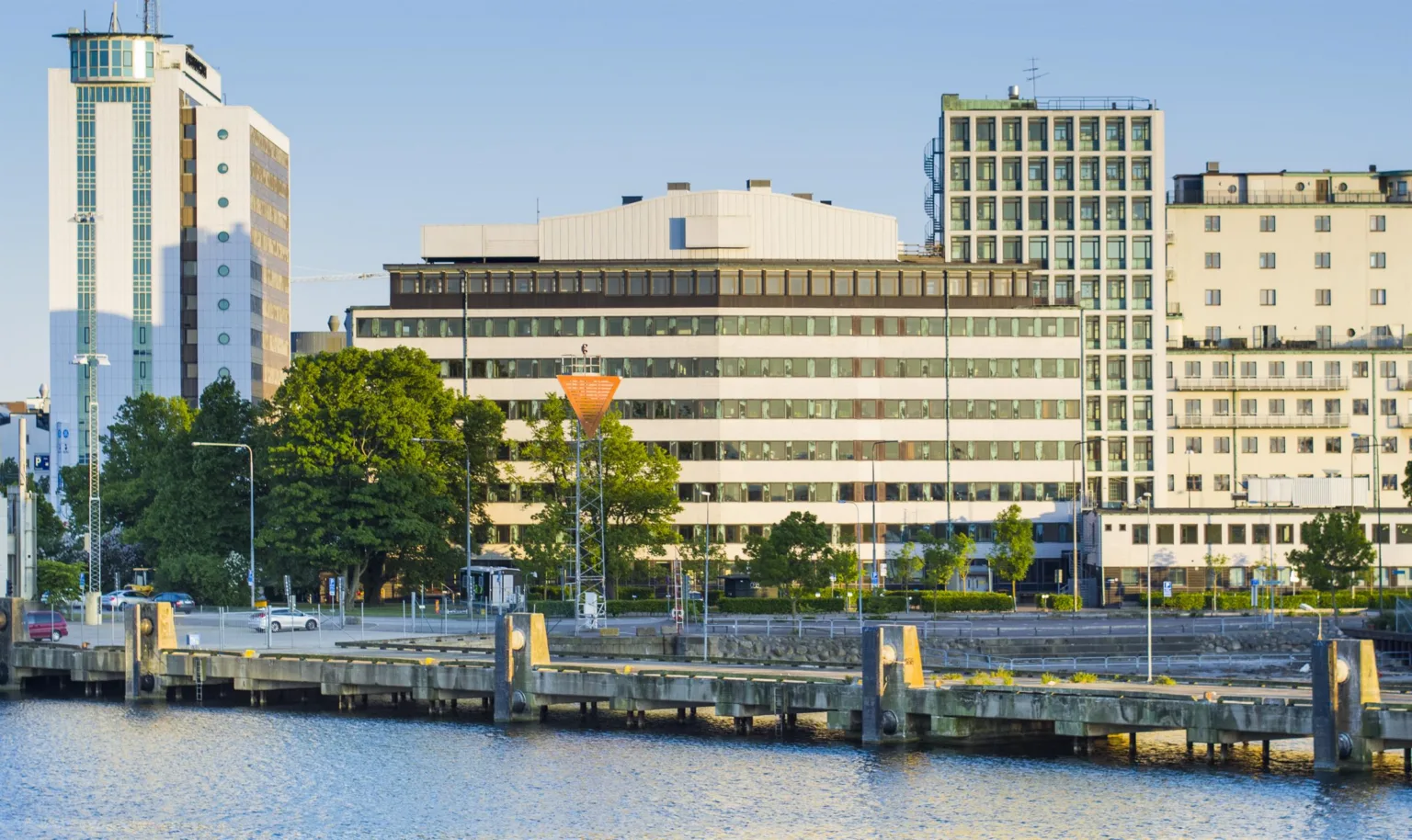 En modern kontorsbyggnad med stora fönster och utsikt över en kaj.