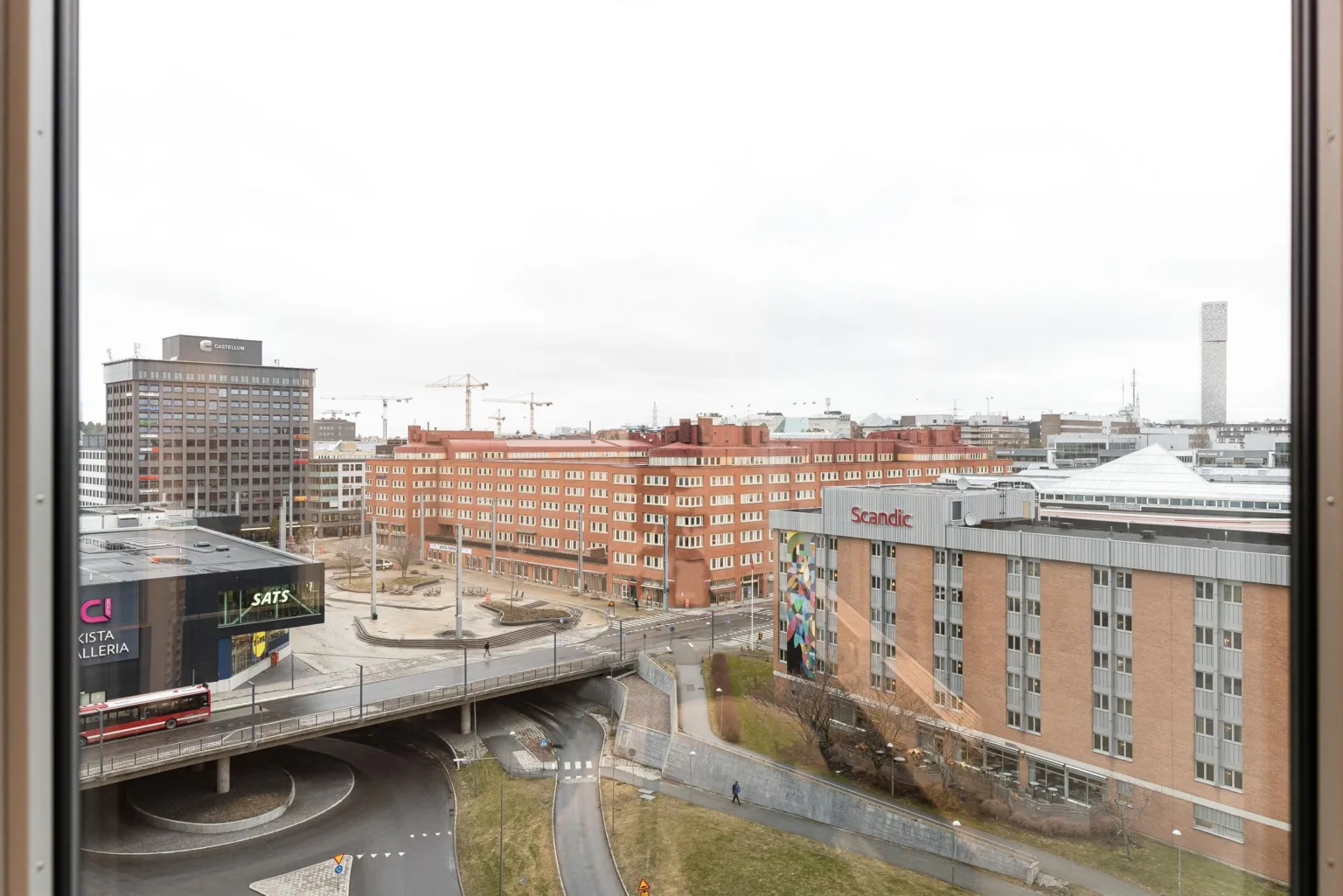 3. En utsikt över en stadsmiljö med byggnader, en bro och grönområden under en molnig himmel.