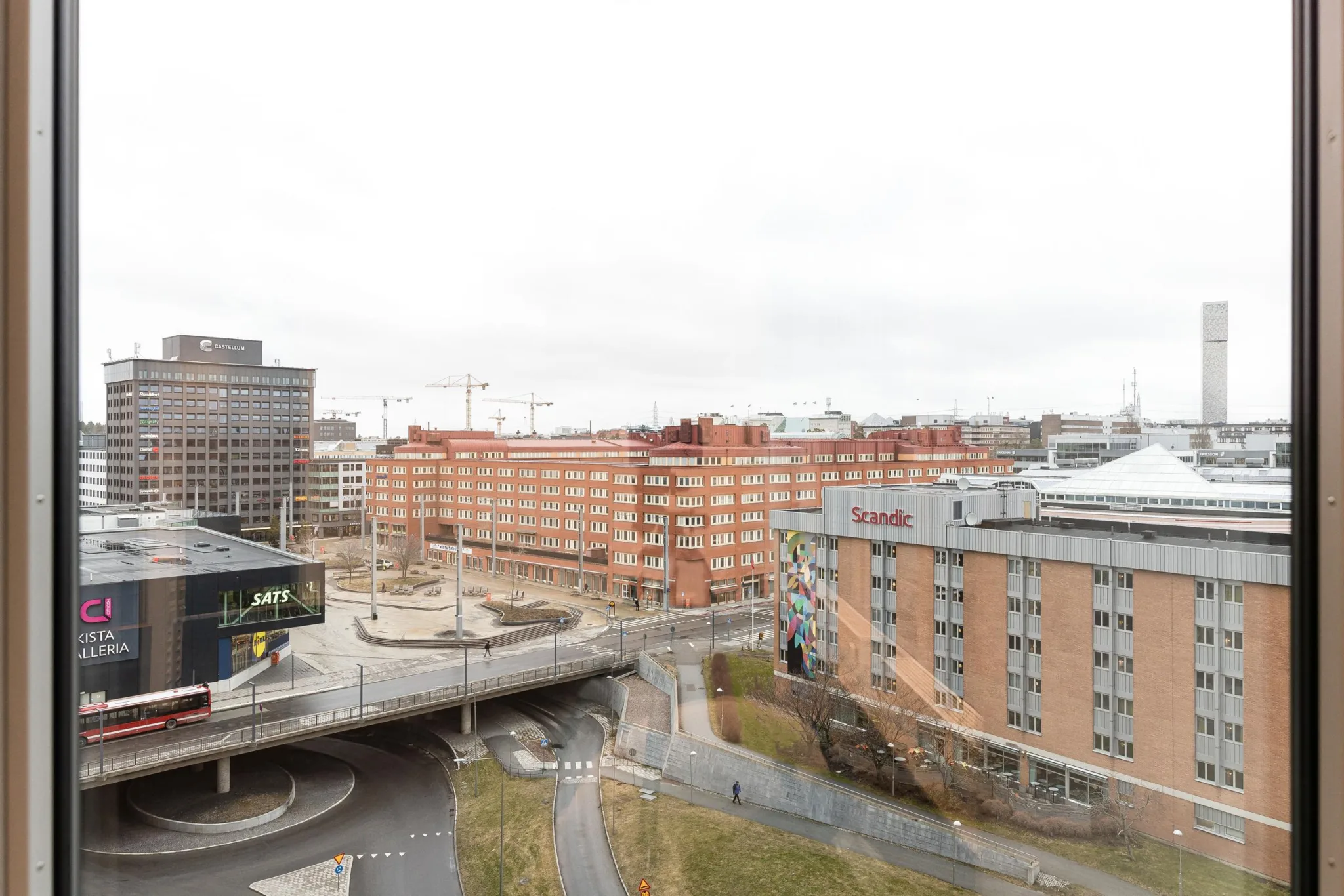 3. En utsikt över en stadsmiljö med byggnader, en bro och grönområden under en molnig himmel.