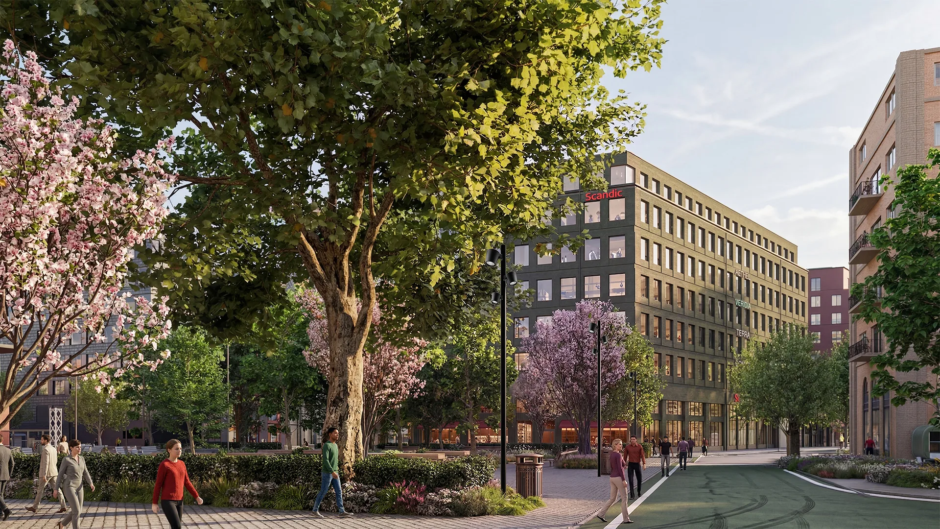 En stadsmiljö med ett stort träd, blommande buskar och en modern byggnad i bakgrunden.