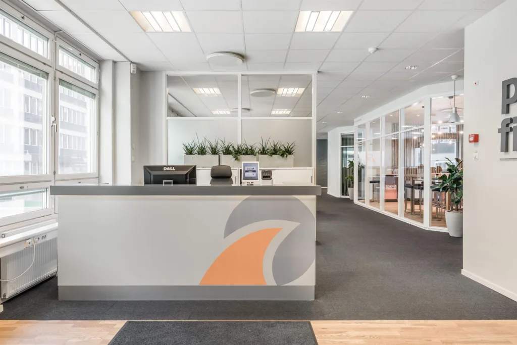 5. En reception med en vit disk dekorerad med en orange och grå design, kontorsmiljö i bakgrunden.