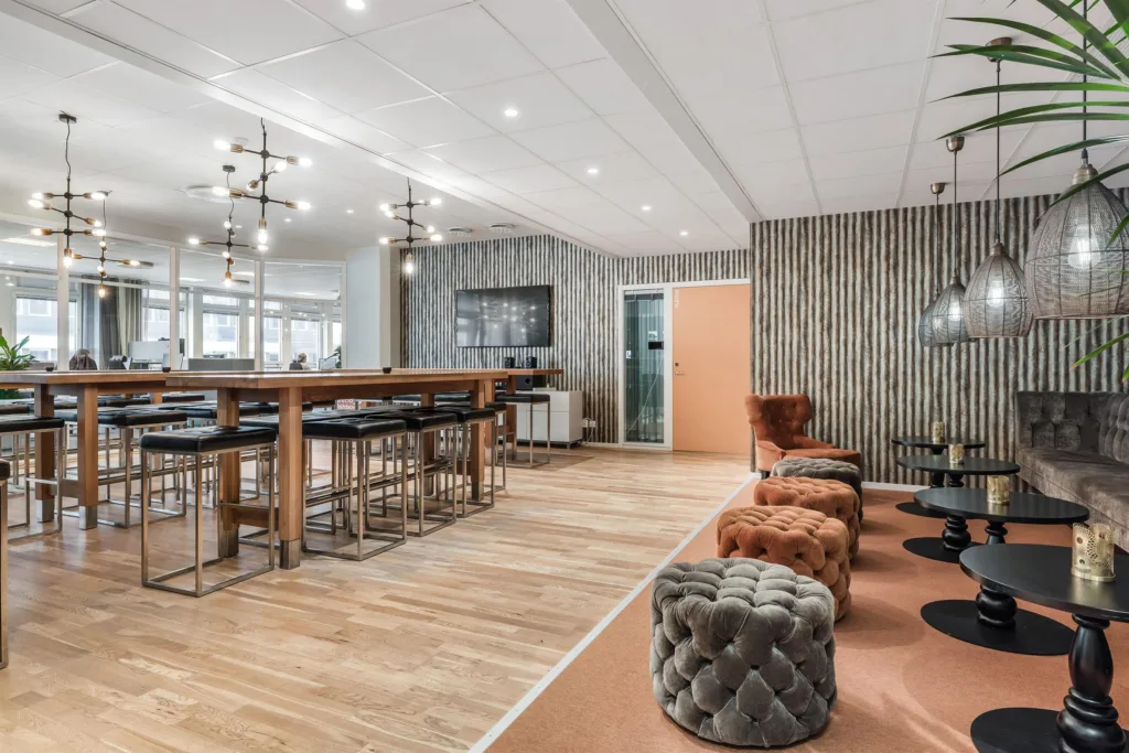 4. Ett stilrent loungeområde med sittpuffar, höga bord och träinredning.