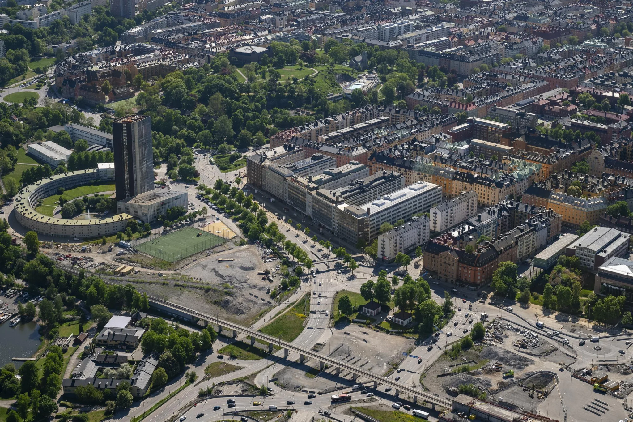 4. Flygbild över stadsmiljö med byggnader, parker och vägar under en klar dag.