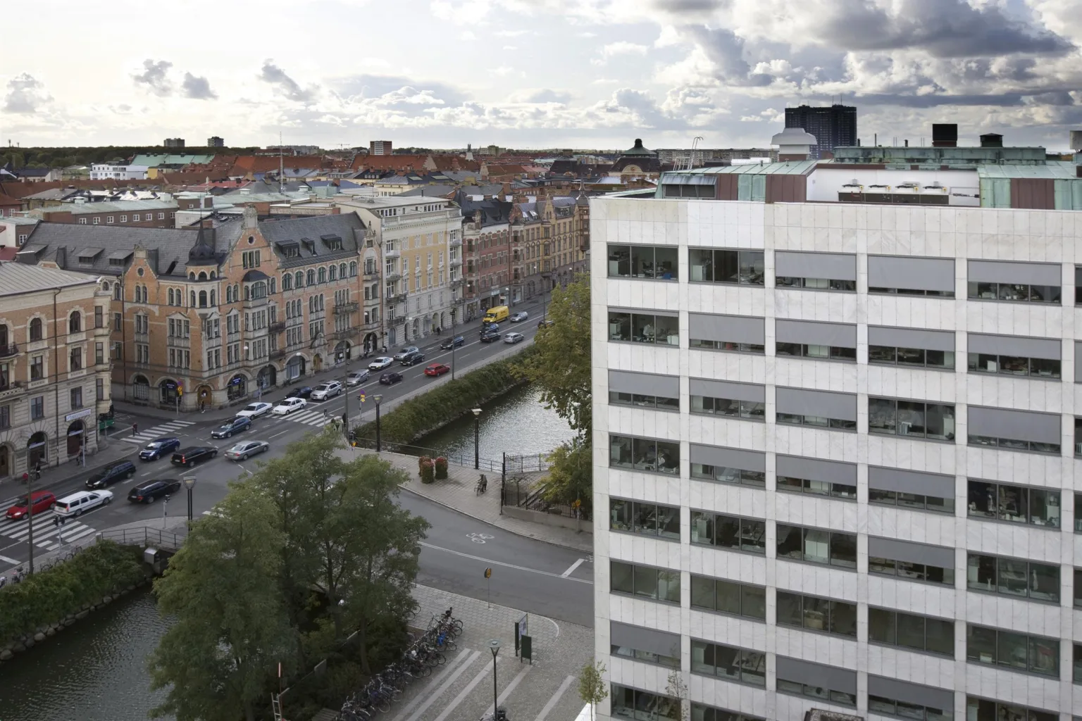 Utsikt över en stad, med byggnader, gator och ett vitt höghus i förgrunden.