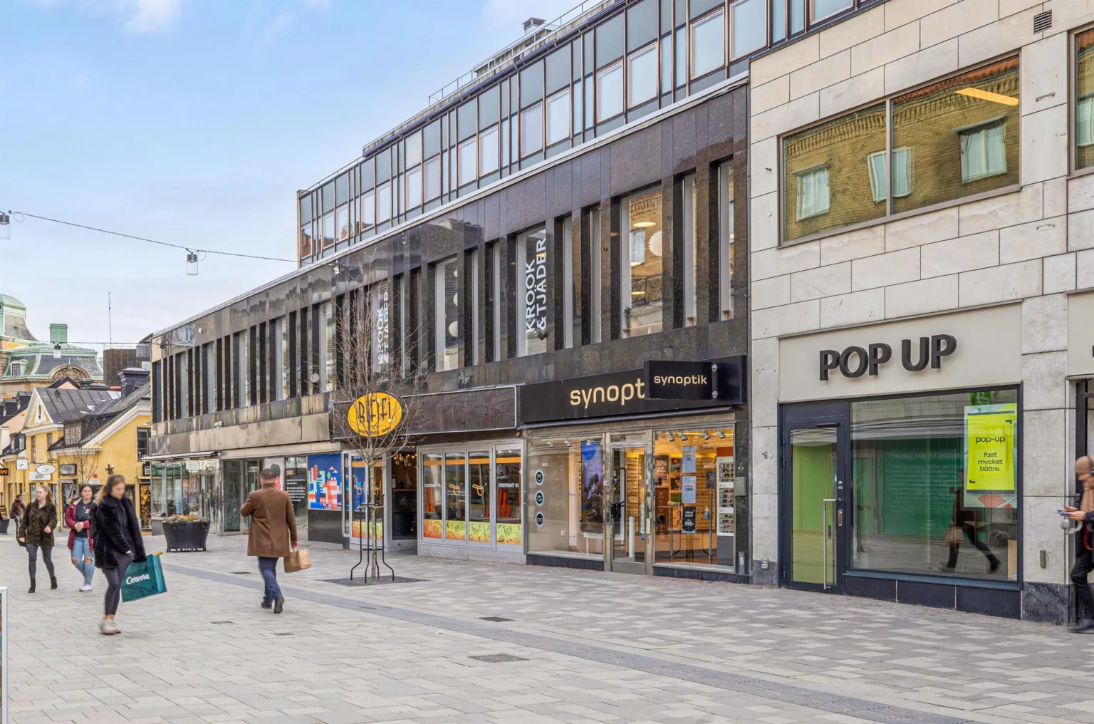 3. En stadsgata med butiker, inklusive skyltar för "Swopt" och "Pop".