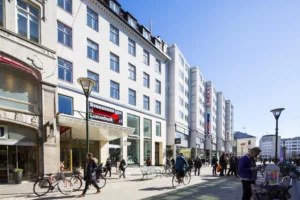 3. En gata med människor, cyklar och en rad vita byggnader med butiker.