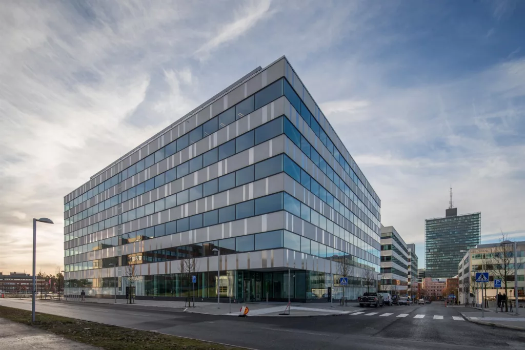 3. En modern byggnad med glasfasad och flera våningar under en molnig himmel.
