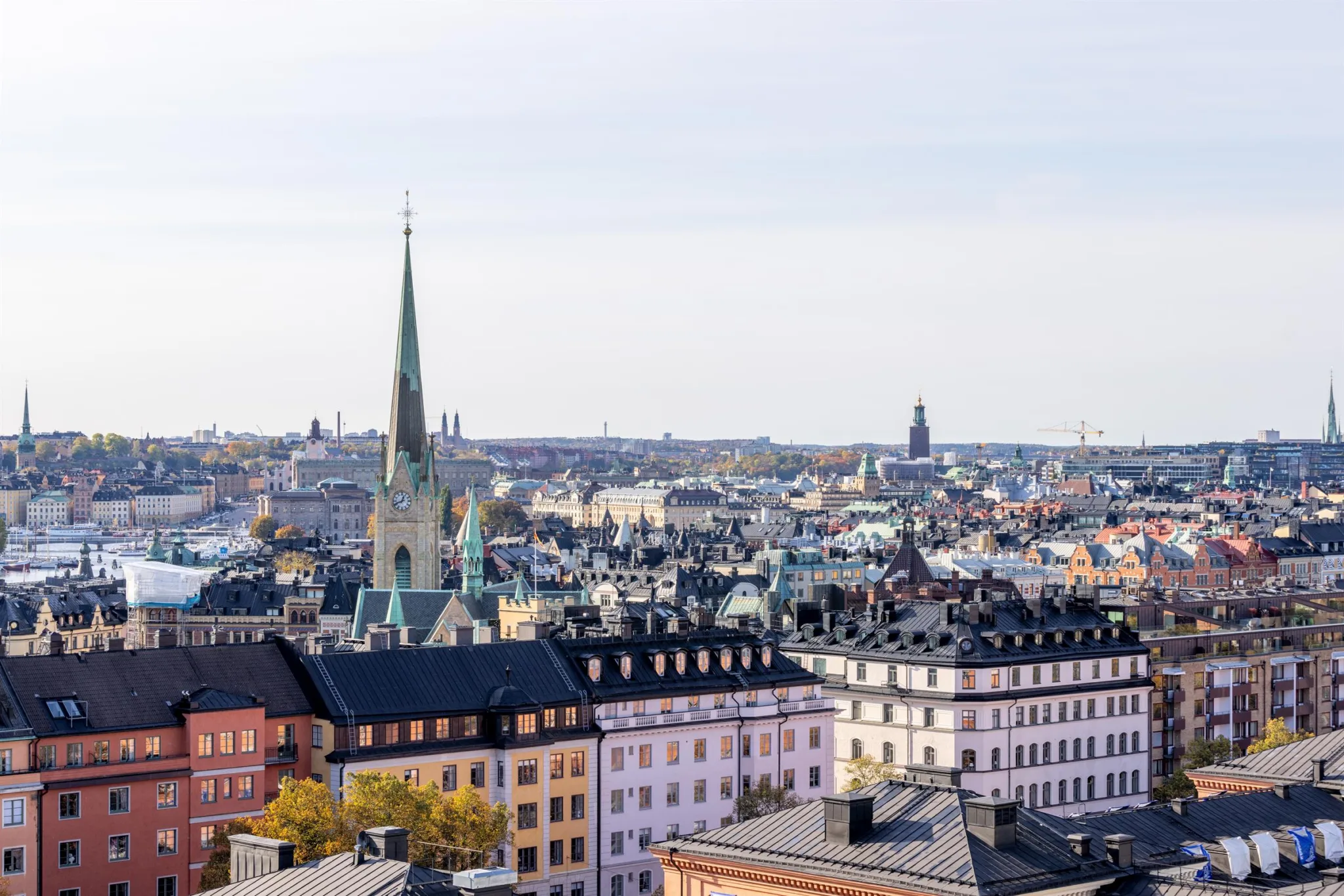Stadsvy med kyrktorn, byggnader och tak i olika färger.