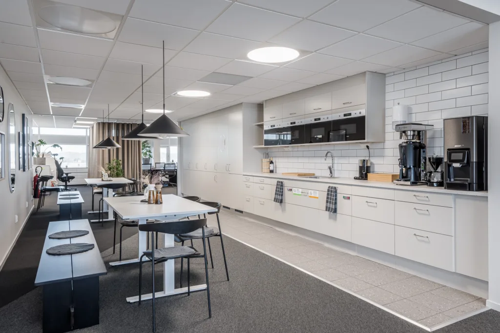 3. Ett modernt kontorspentry med vita skåp, svarta stolar och arbetsbänkar.
