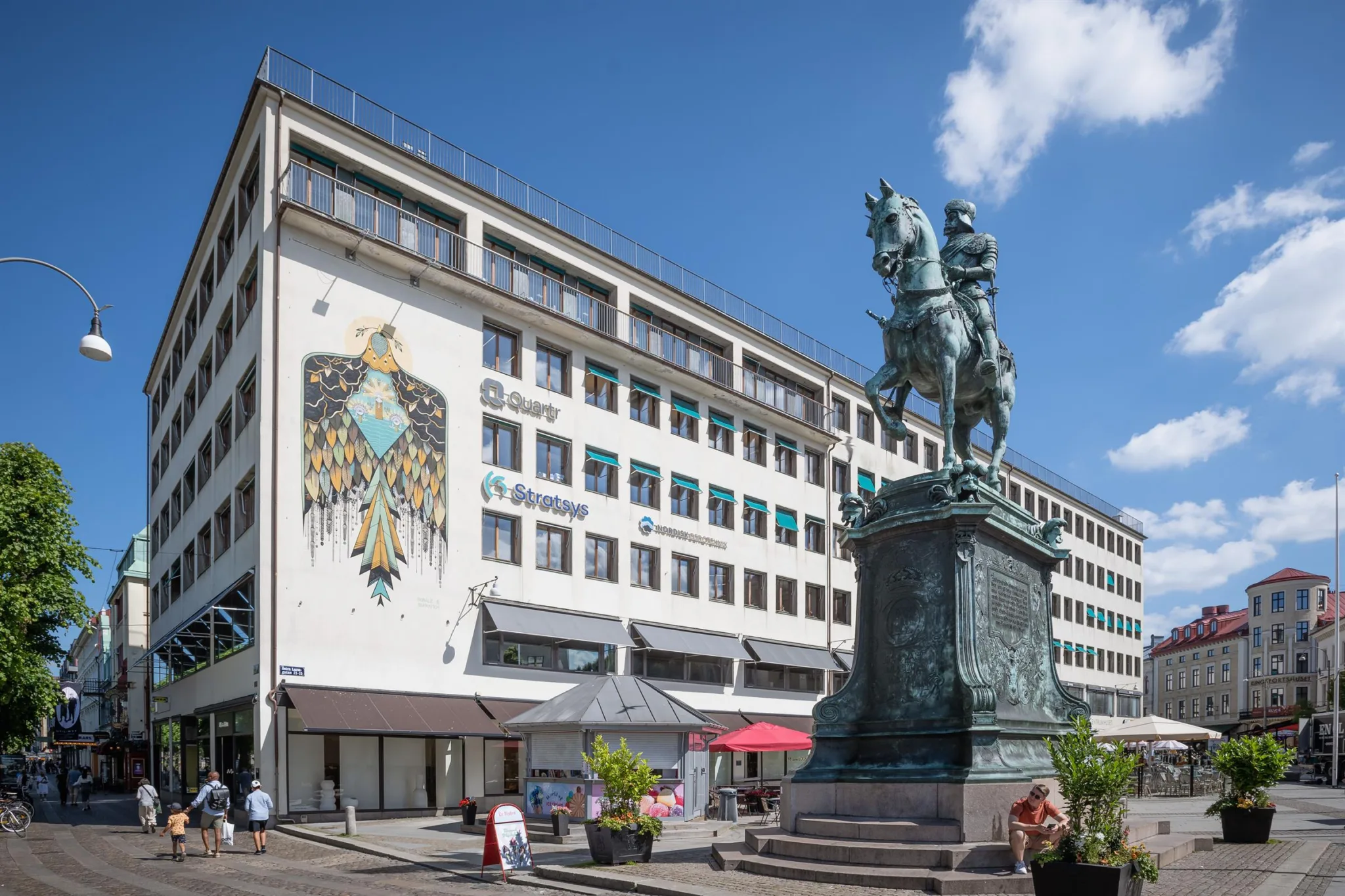 2. En staty av en ryttare framför en byggnad med en stor väggmålning av en fågel.