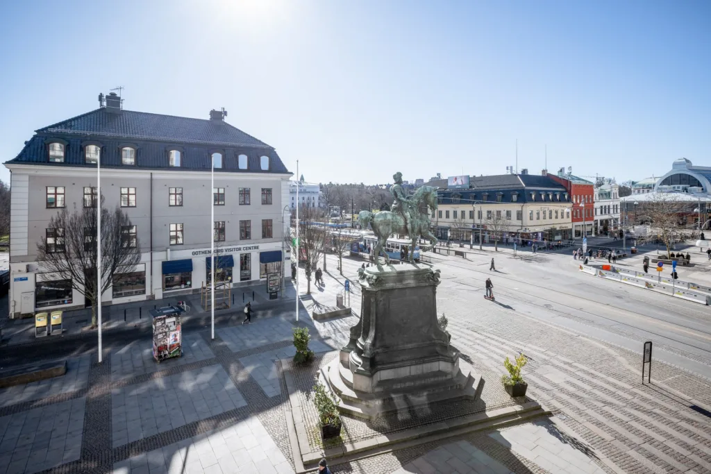 4. En öppen stadsplats med staty och kringliggande byggnader under en klarblå himmel.