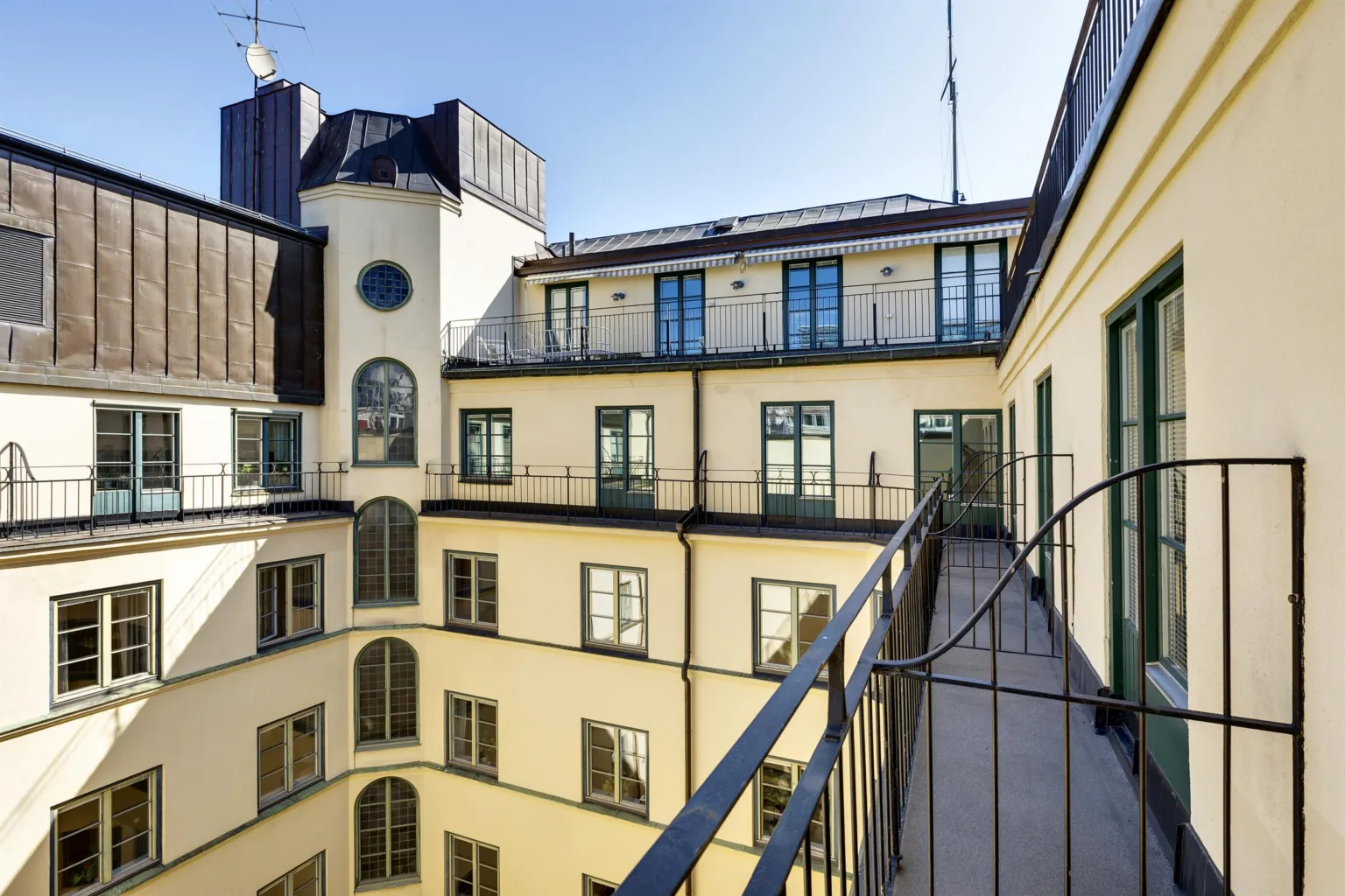 En innegård med en balkong och utsikt över fasader med stora fönster och klassisk arkitektur.