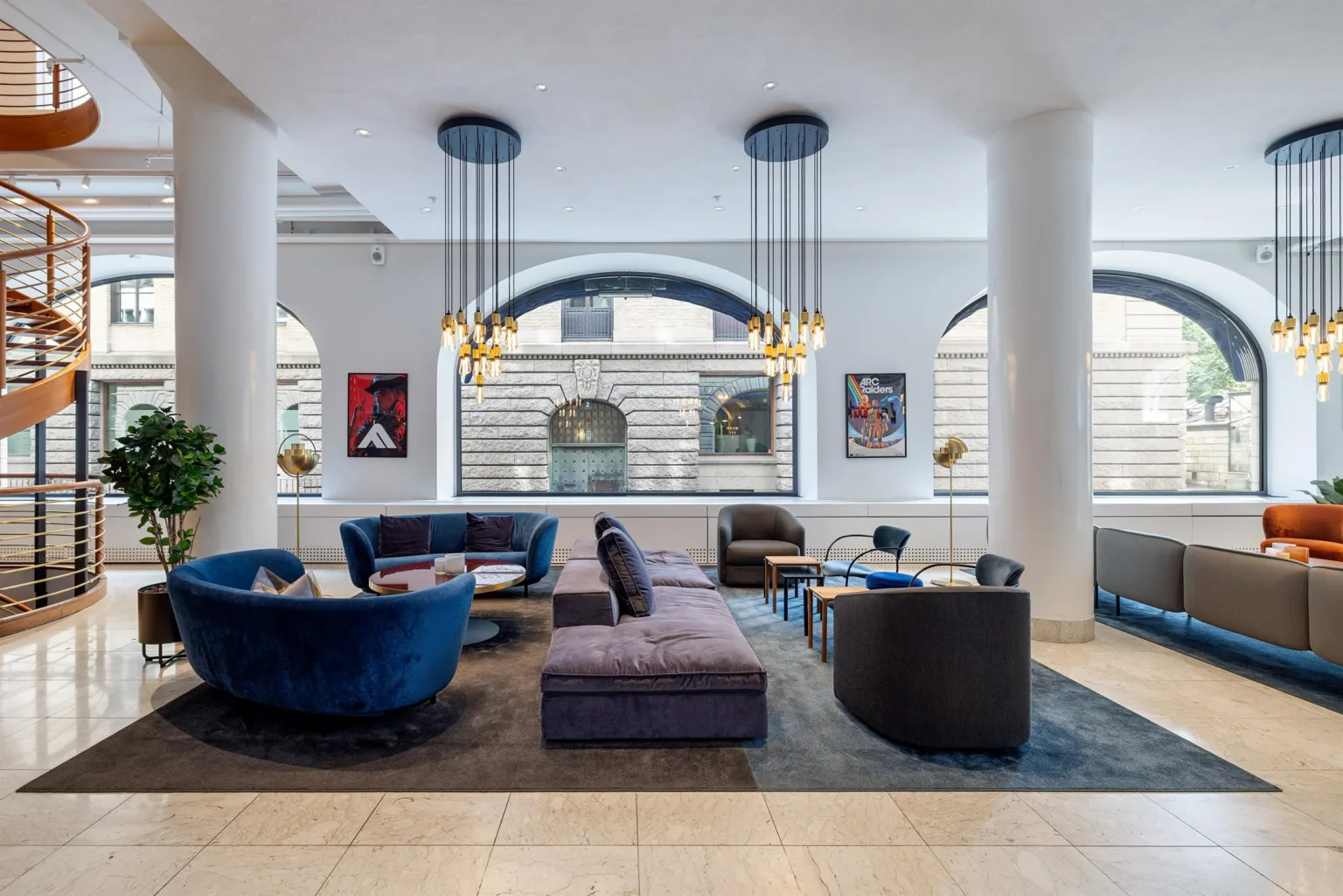 Ett stilrent vardagsrum med blå och lila soffor samt stora fönster.