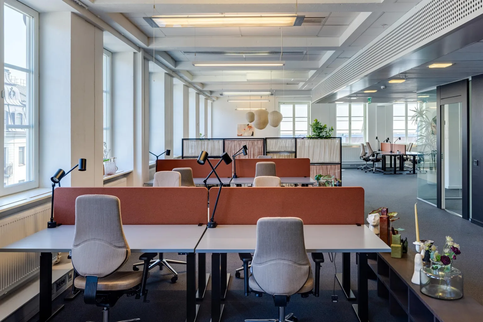 En modern kontorsmiljö med skrivbord, ergonomiska stolar och belysning.