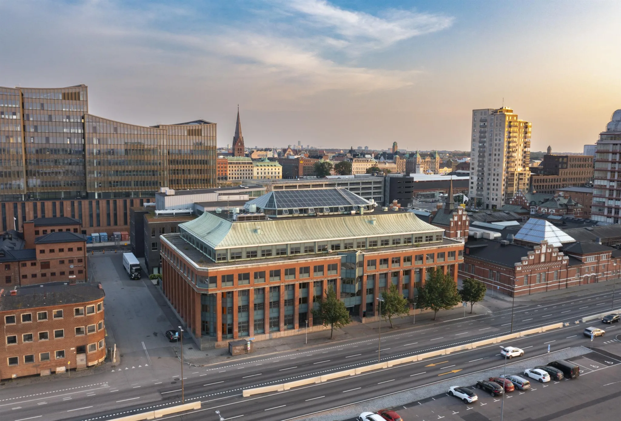 5. En stadsbild med en tegelbyggnad i förgrunden och en kyrkspira i bakgrunden.
