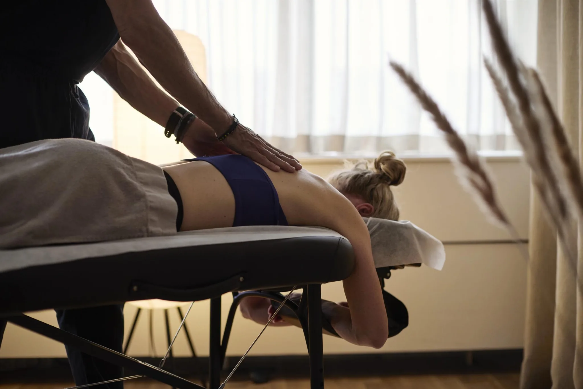 En person får massage liggande på en massagebänk i ett rum med mjuk belysning.