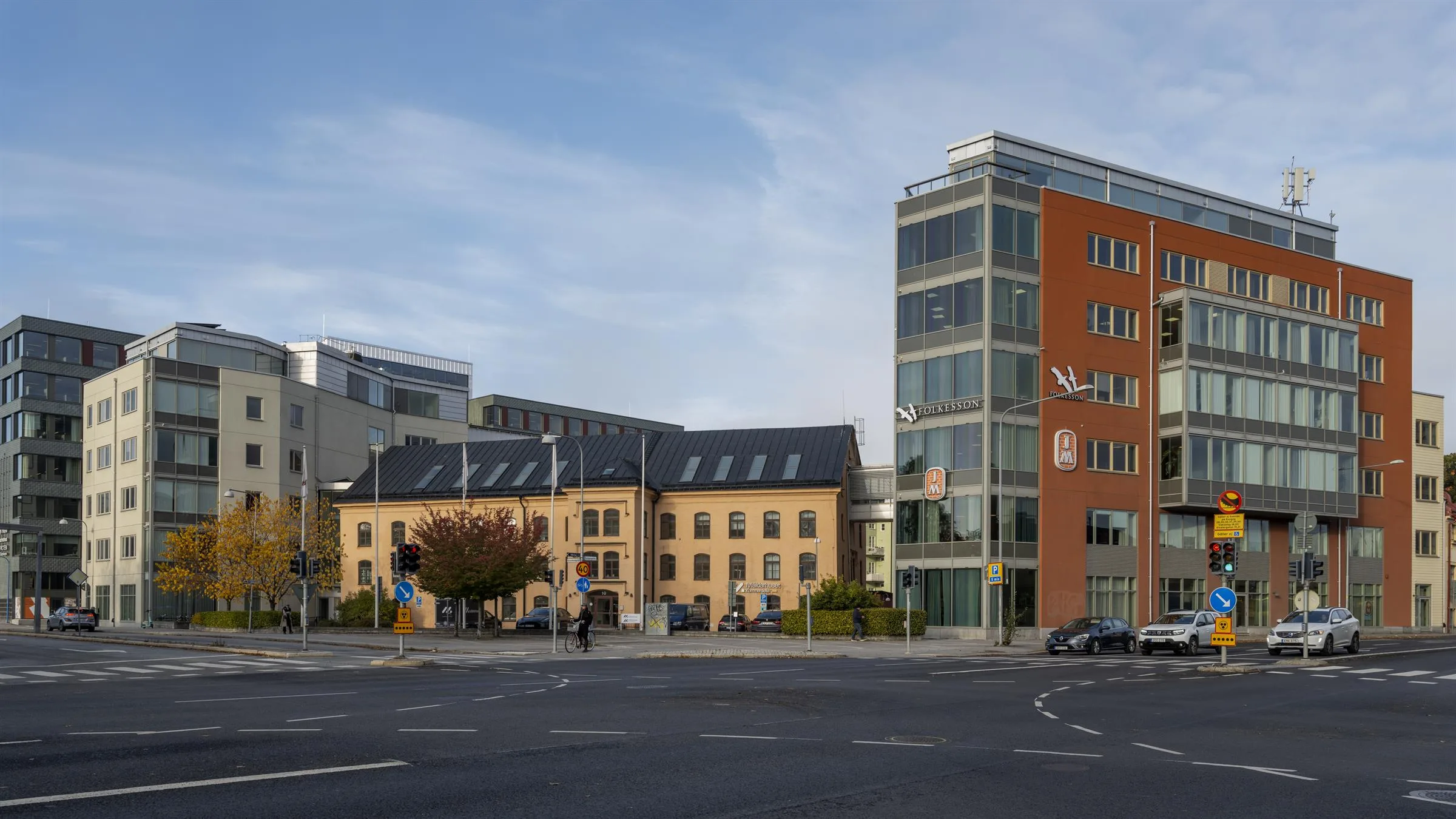 En stadsmiljö med moderna och äldre byggnader vid en bred gata.