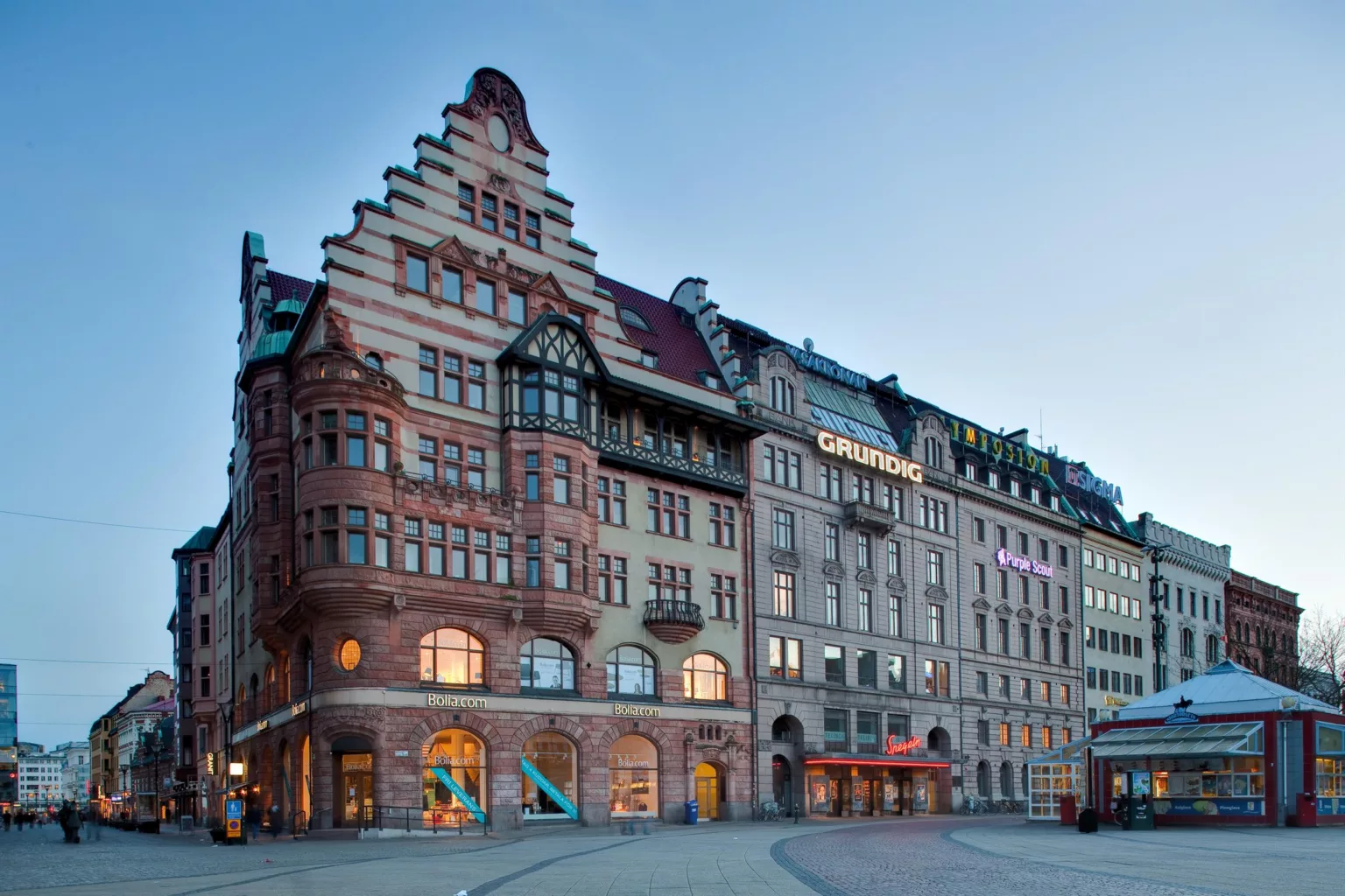 3. En större byggnad med trappstegsformad takfasad och detaljerade fönster, omgiven av stadsmiljö.
