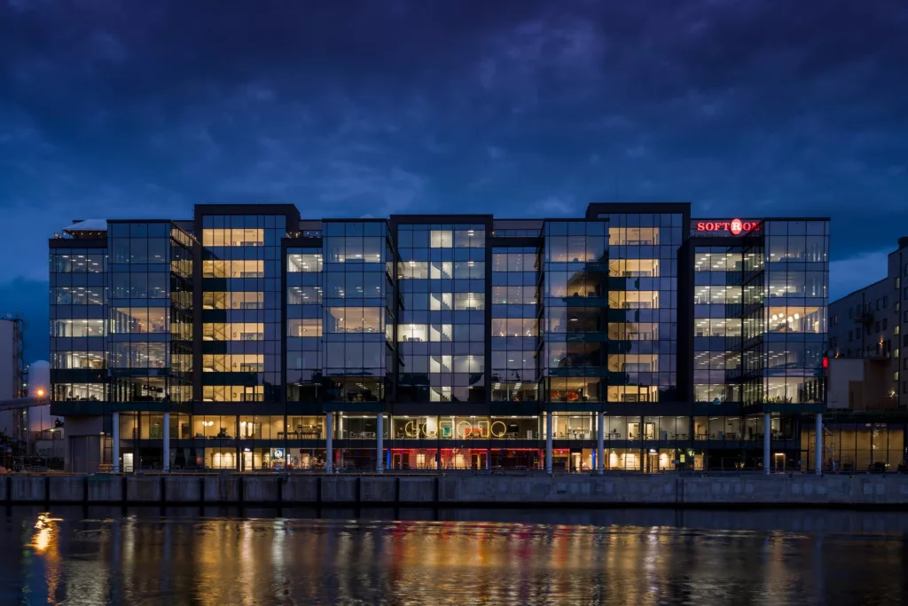 En modern byggnad med upplysta fönster vid en kanal på kvällen.