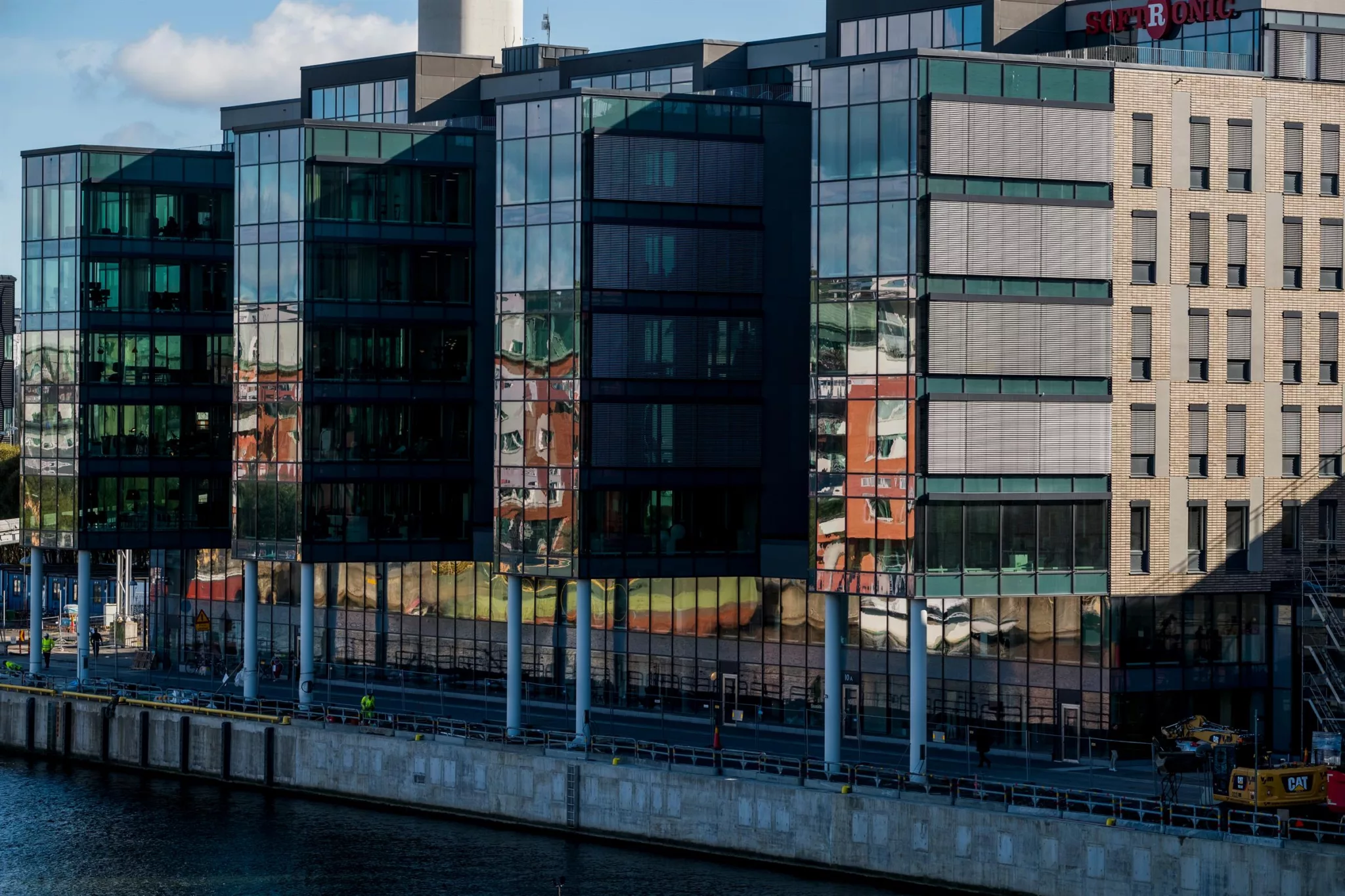 En modern byggnad med glasfasad vid en kanal under dagsljus.