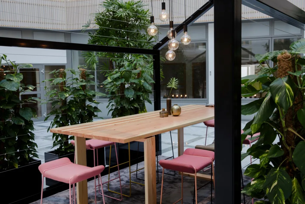 2. Ett uterum med trämöbler, rosa sittdynor och omgivande växtlighet.