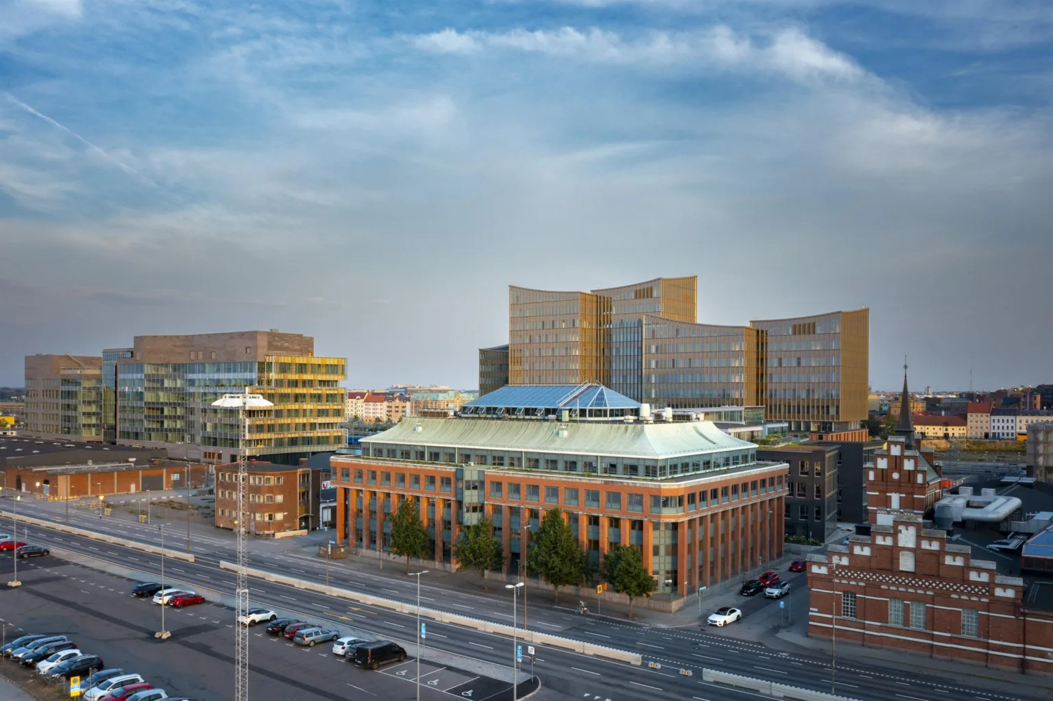 4. En stadsvy med moderna byggnader och en väg i förgrunden under en blå himmel.