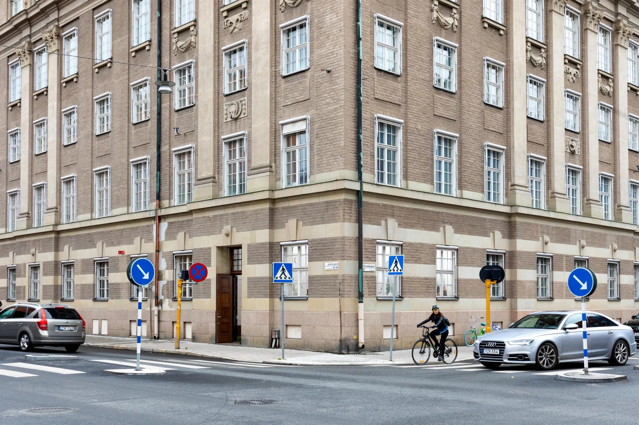 En hörnbyggnad i tegel med flera fönster och cyklist på gatan framför.