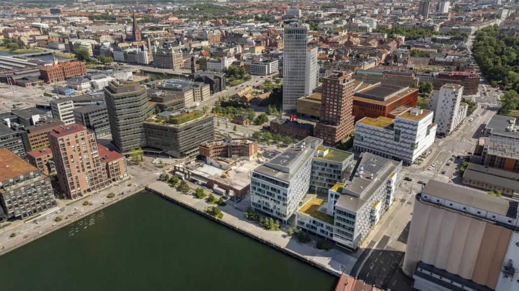 Flygvy över en stad med moderna byggnader, en kanal och en blandning av arkitektur.