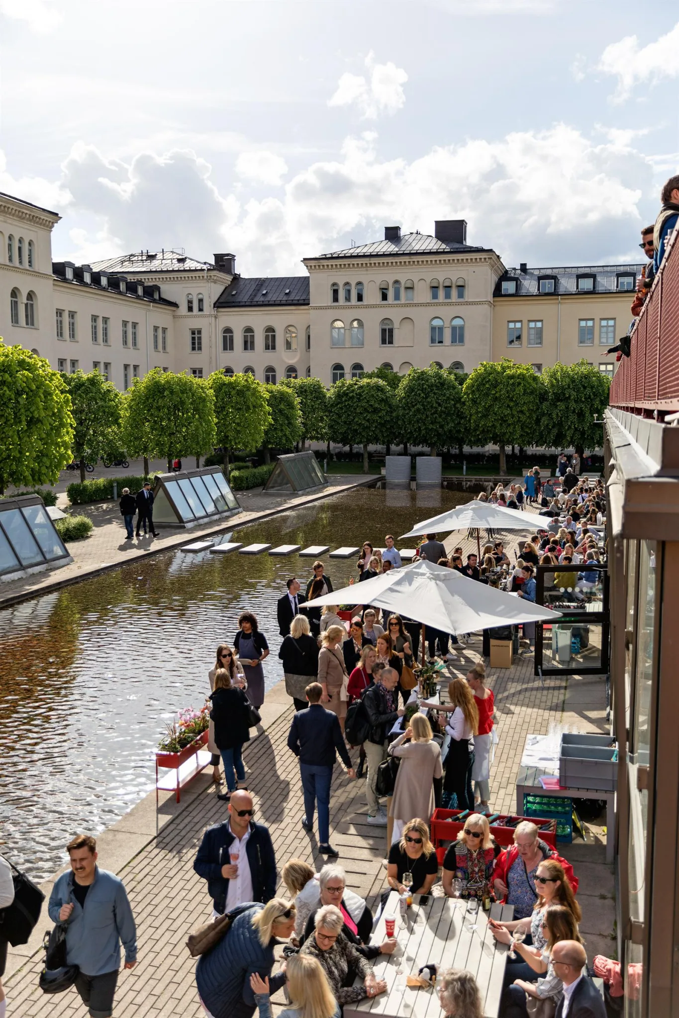 4. Livlig gata vid en kanal med människor, parasoller och omgivande byggnader.