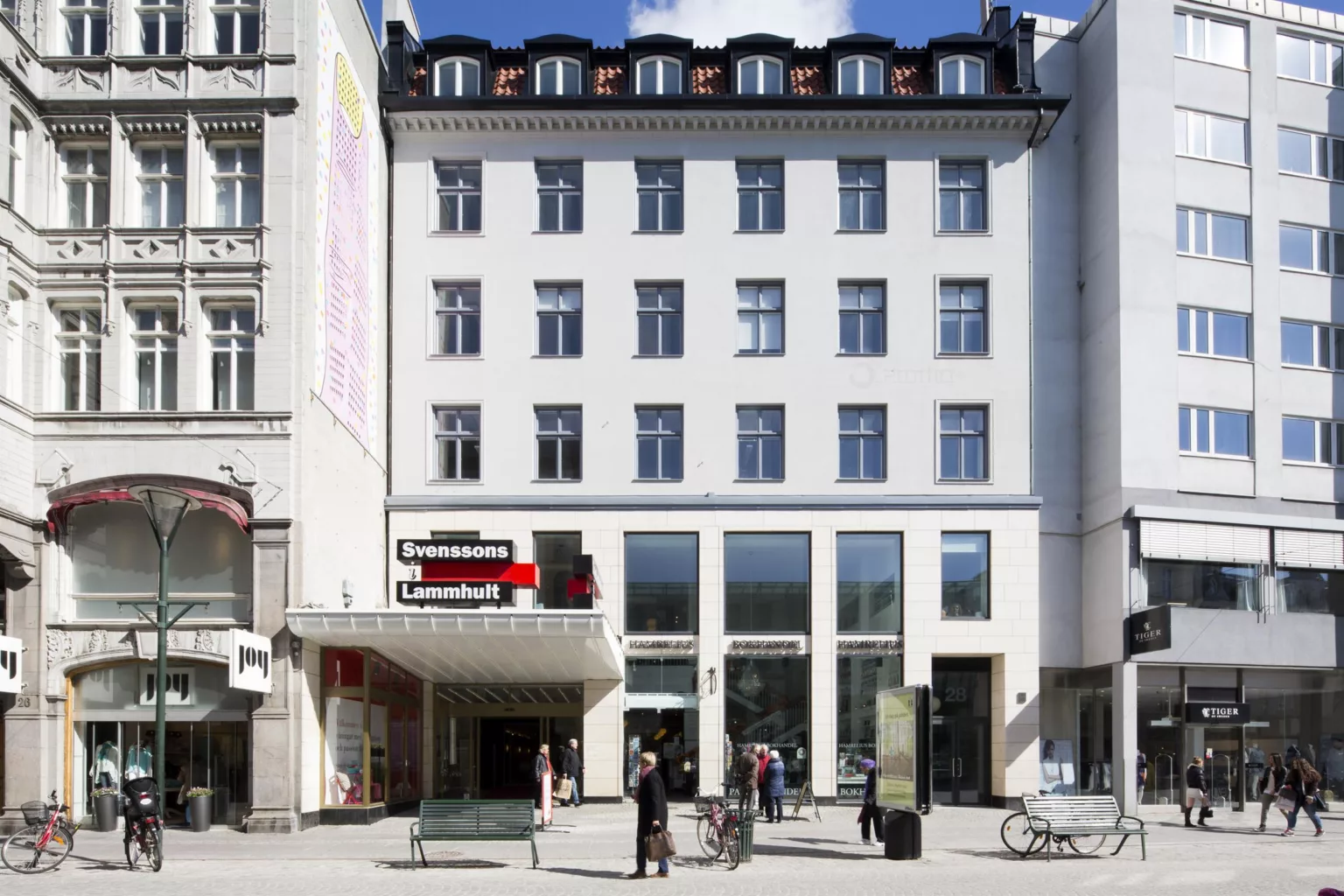 En vit byggnad med flera våningar, stora fönster och en röd skylt med texten "Kulturhuset Stadsteatern". Människor står utanför entrén.