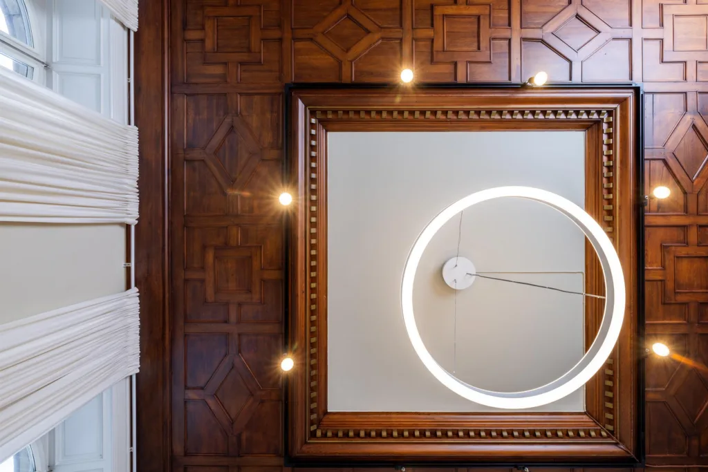 Takdetaljer med träpaneler, en modern cirkelformad lampa och dekorativa mönster.