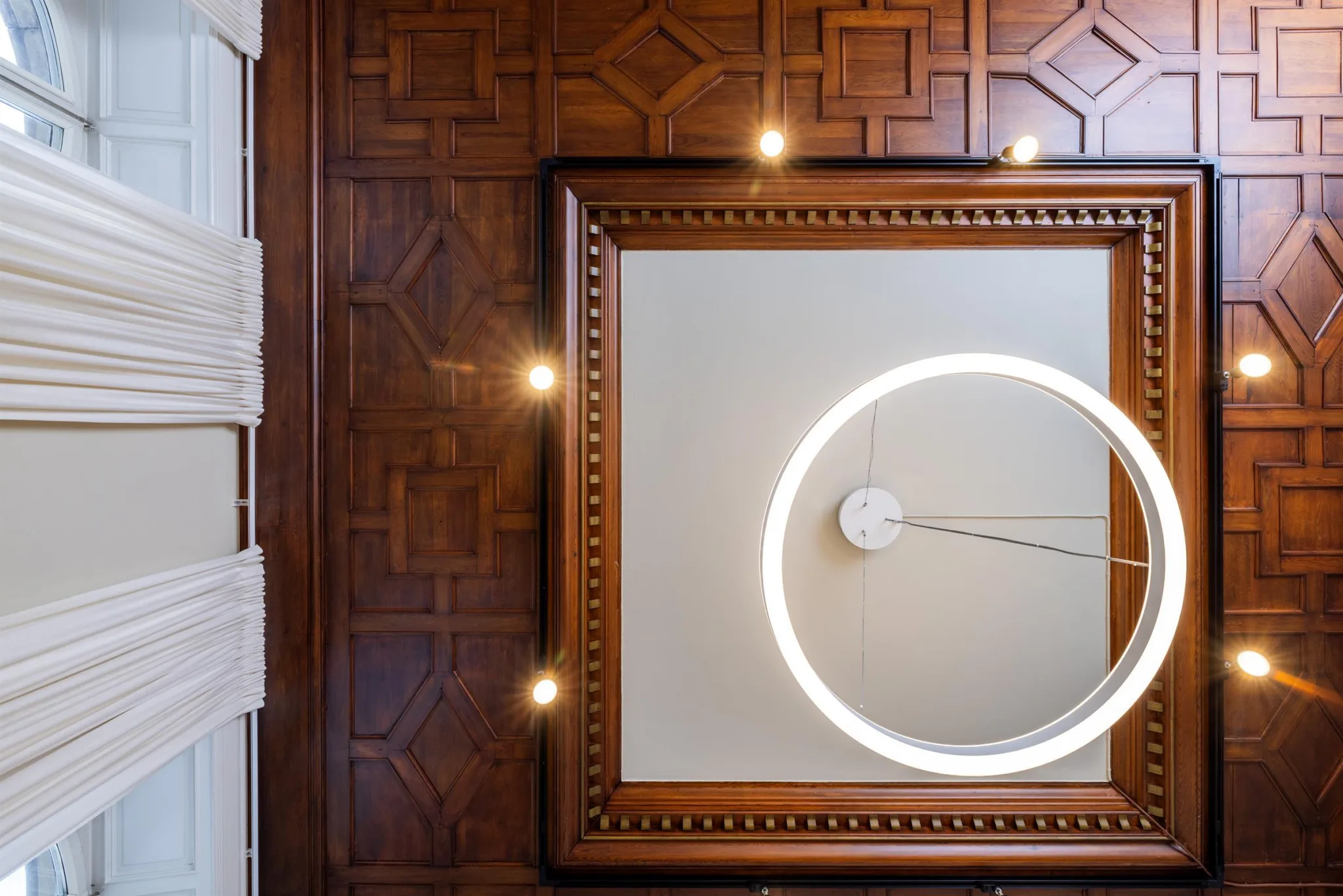 Takdetaljer med träpaneler, en modern cirkelformad lampa och dekorativa mönster.