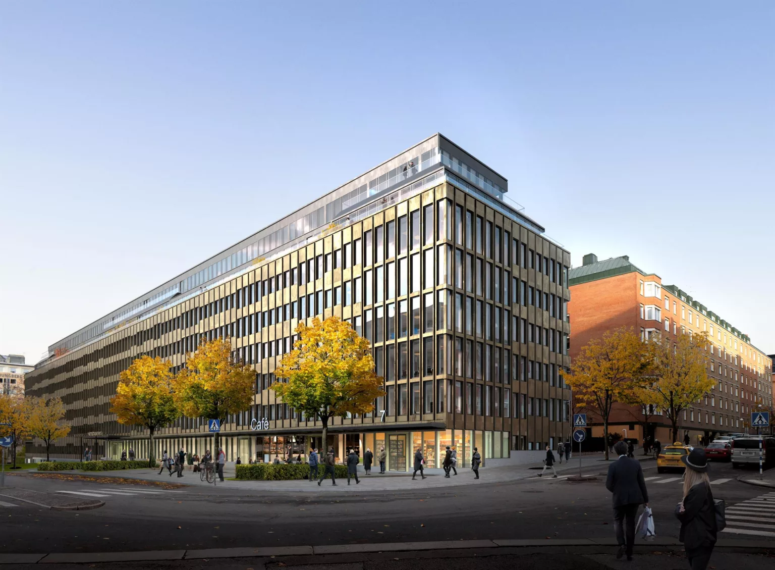 En hörnbyggnad med glasfasad, omgiven av höstfärgade träd och människor som promenerar längs trottoaren.