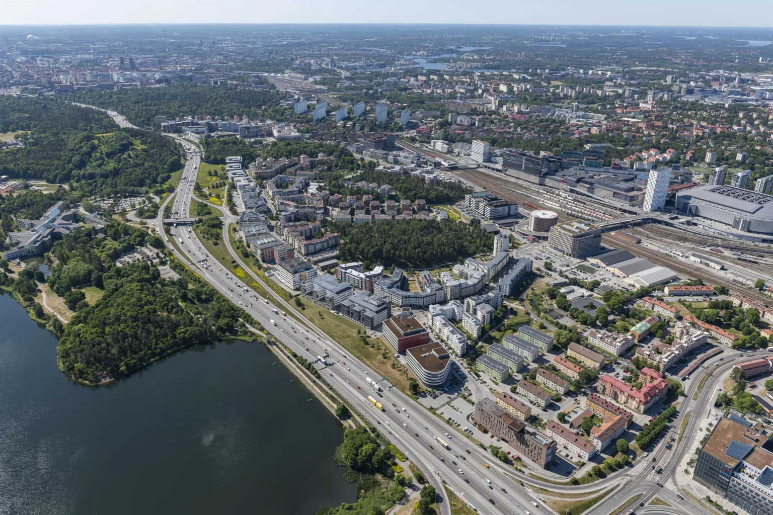 1. Flygfoto över en stadsmiljö med vägar, byggnader och en sjö i förgrunden.