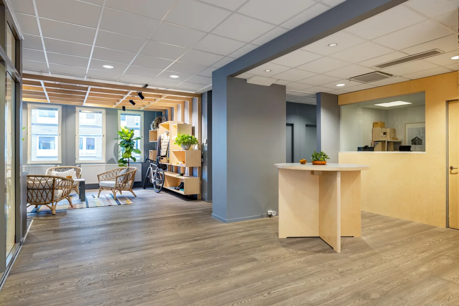 1. Ljus och modern reception med trägolv, grå väggar, växter och sittmöbler.