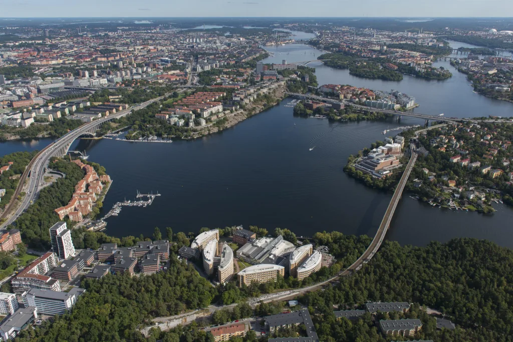 2. Flygfoto över en stad med vatten, broar, grönområden och byggnader.