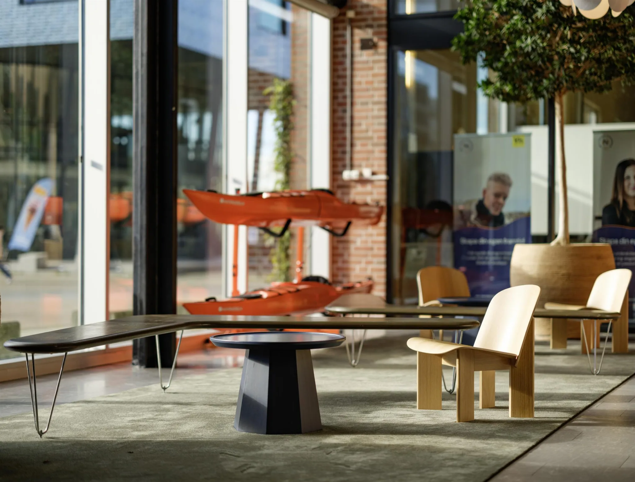 4. Interiör med modern inredning, kajaker monterade på väggen och trästolar i ett öppet och ljust utrymme.