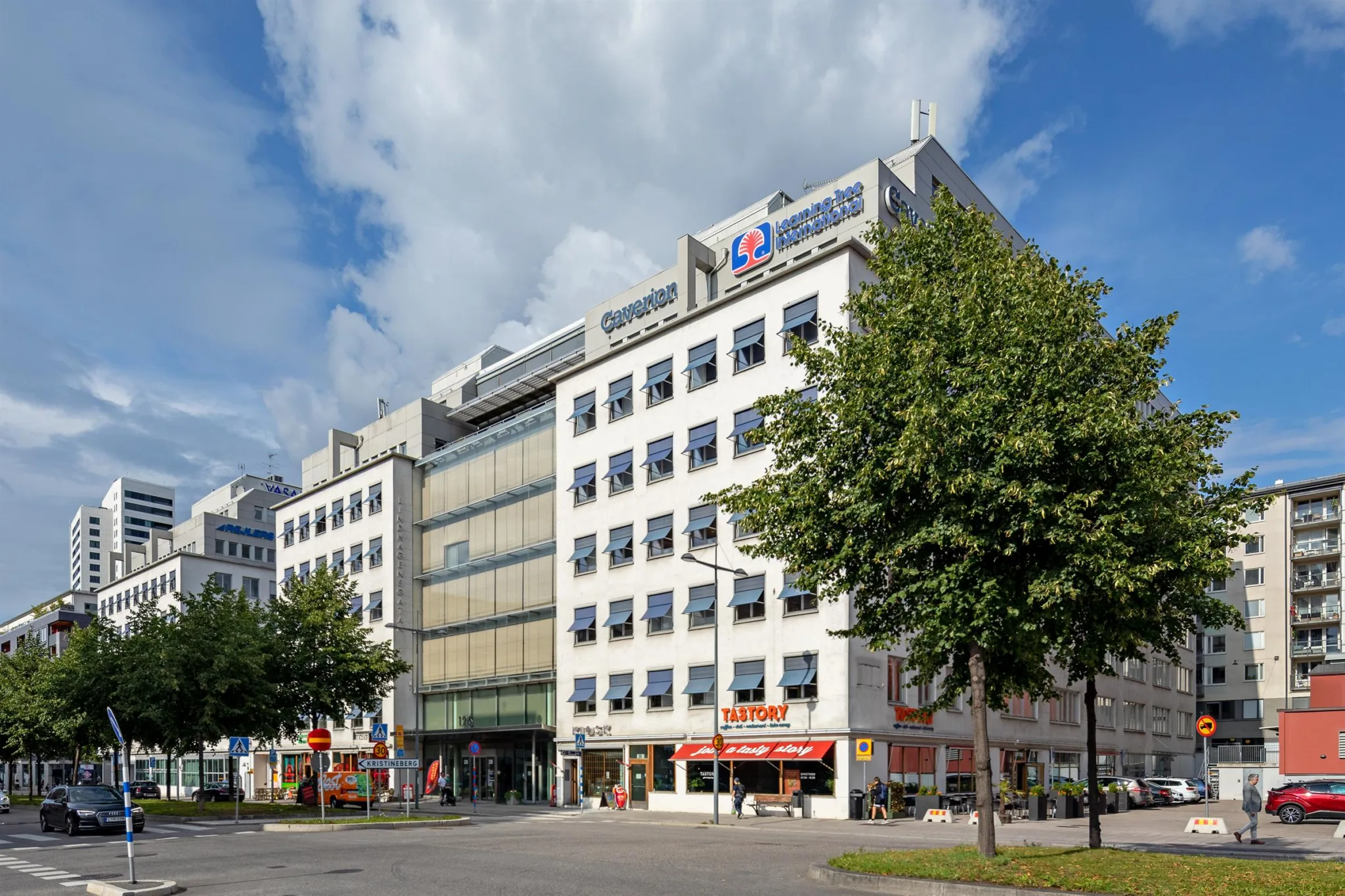 En stadsgata med en flerfaldig byggnad med skyltar för företag och butiker.