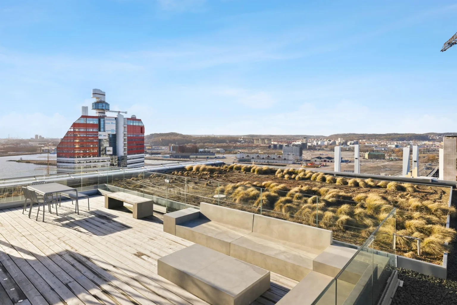 En takterrass med sittplatser, träplattformar och utsikt över staden.