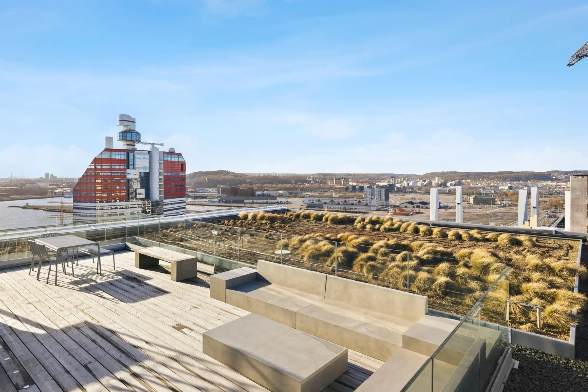 En takterrass med sittplatser, träplattformar och utsikt över staden.