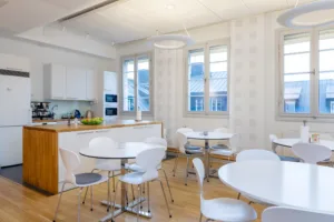 Ett modernt kök och matrum med vita möbler, stora fönster och ljus inredning.