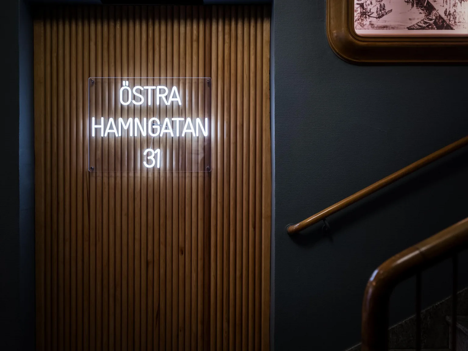 En vägg med texten "ÖSTRA HAMNGATAN 31" i lysande vita bokstäver.