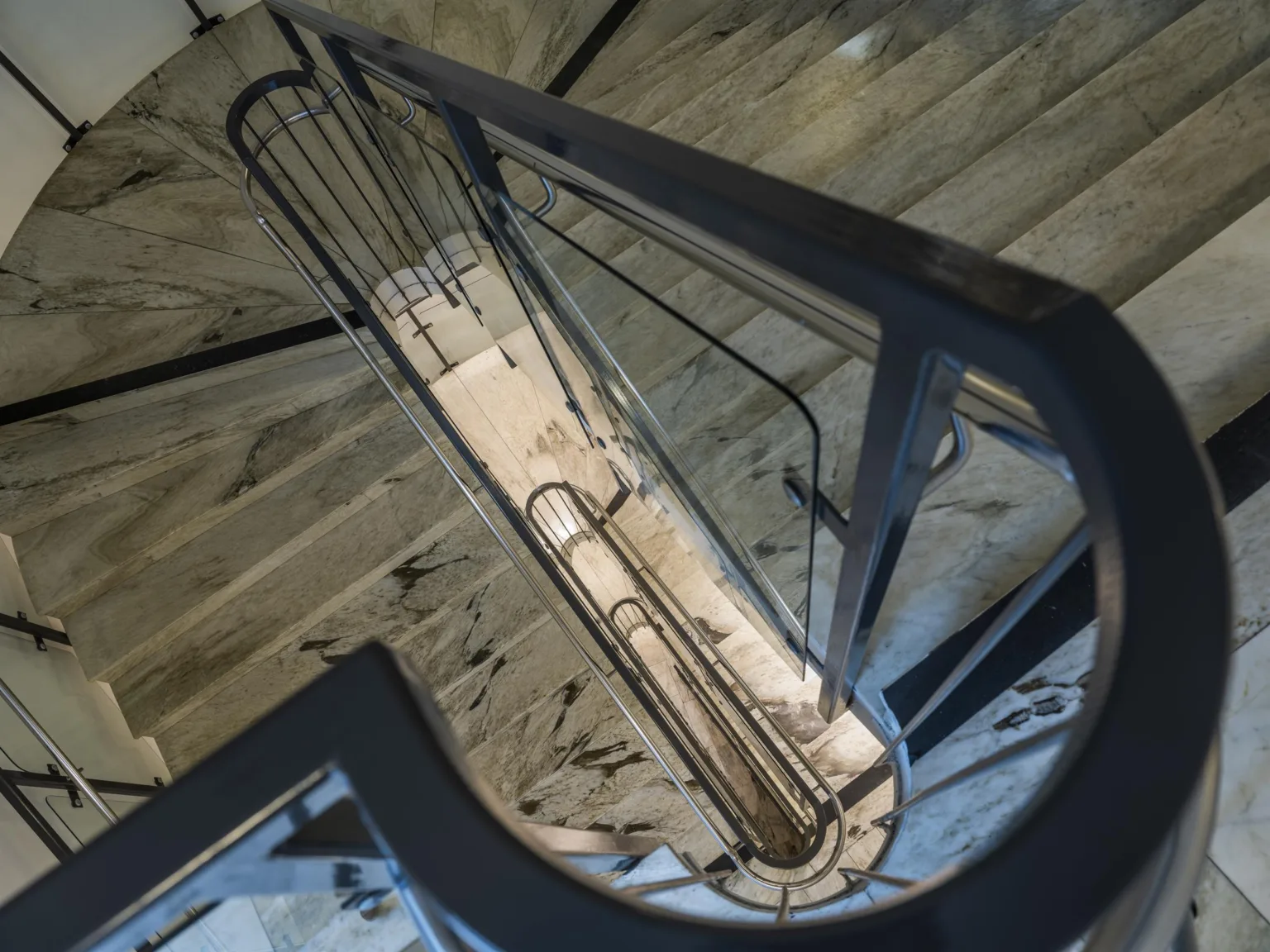 Spiraltrappa med marmorsteg, fotograferad från ovan med fokus på designen.