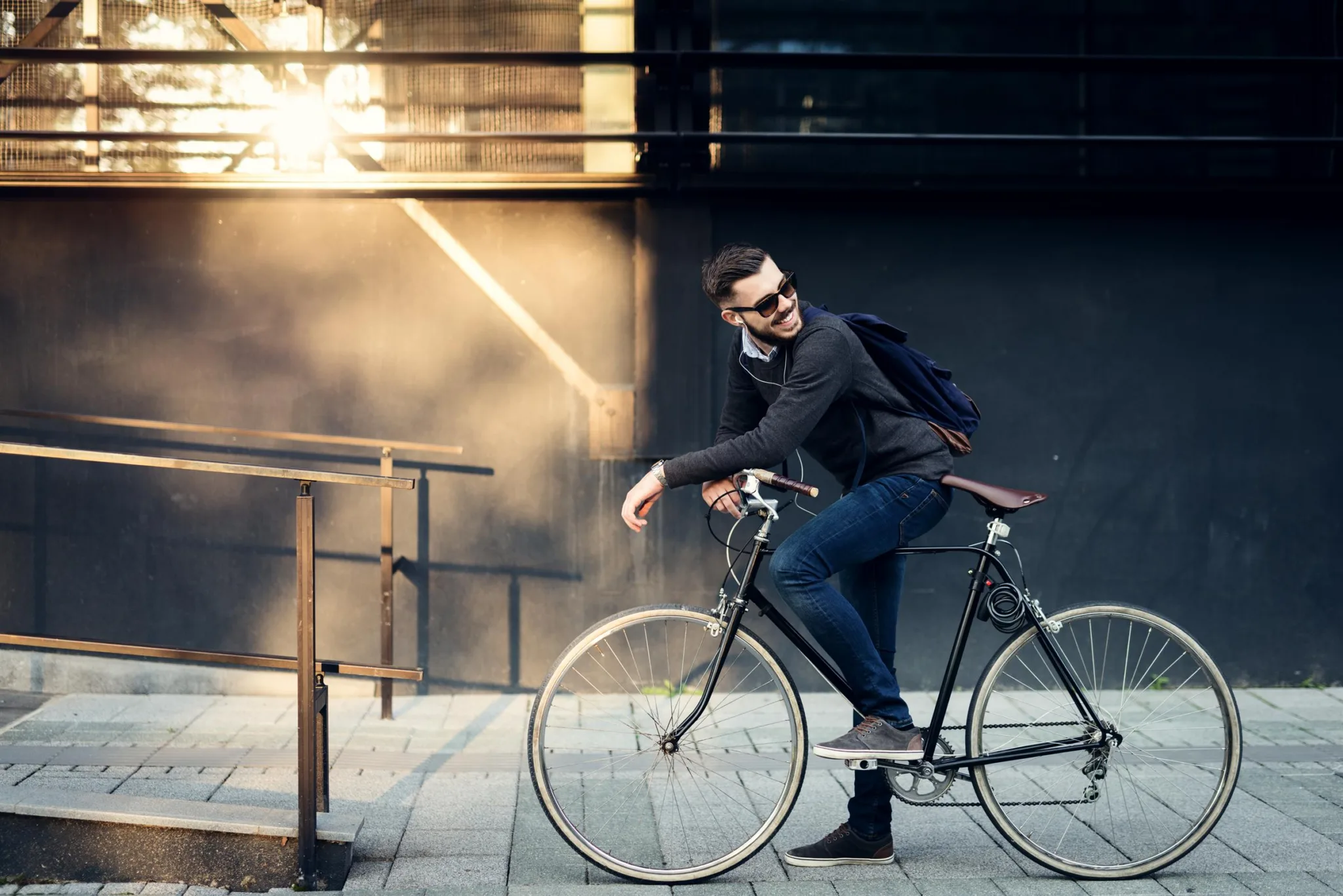 En man cyklar på en stadsgata med solstrålar i bakgrunden.