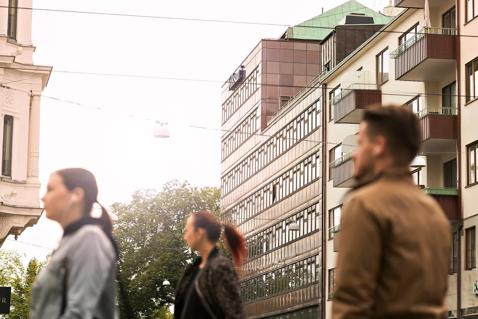 5. Sudda gående människor framför en rad av byggnader i stadsmiljö.