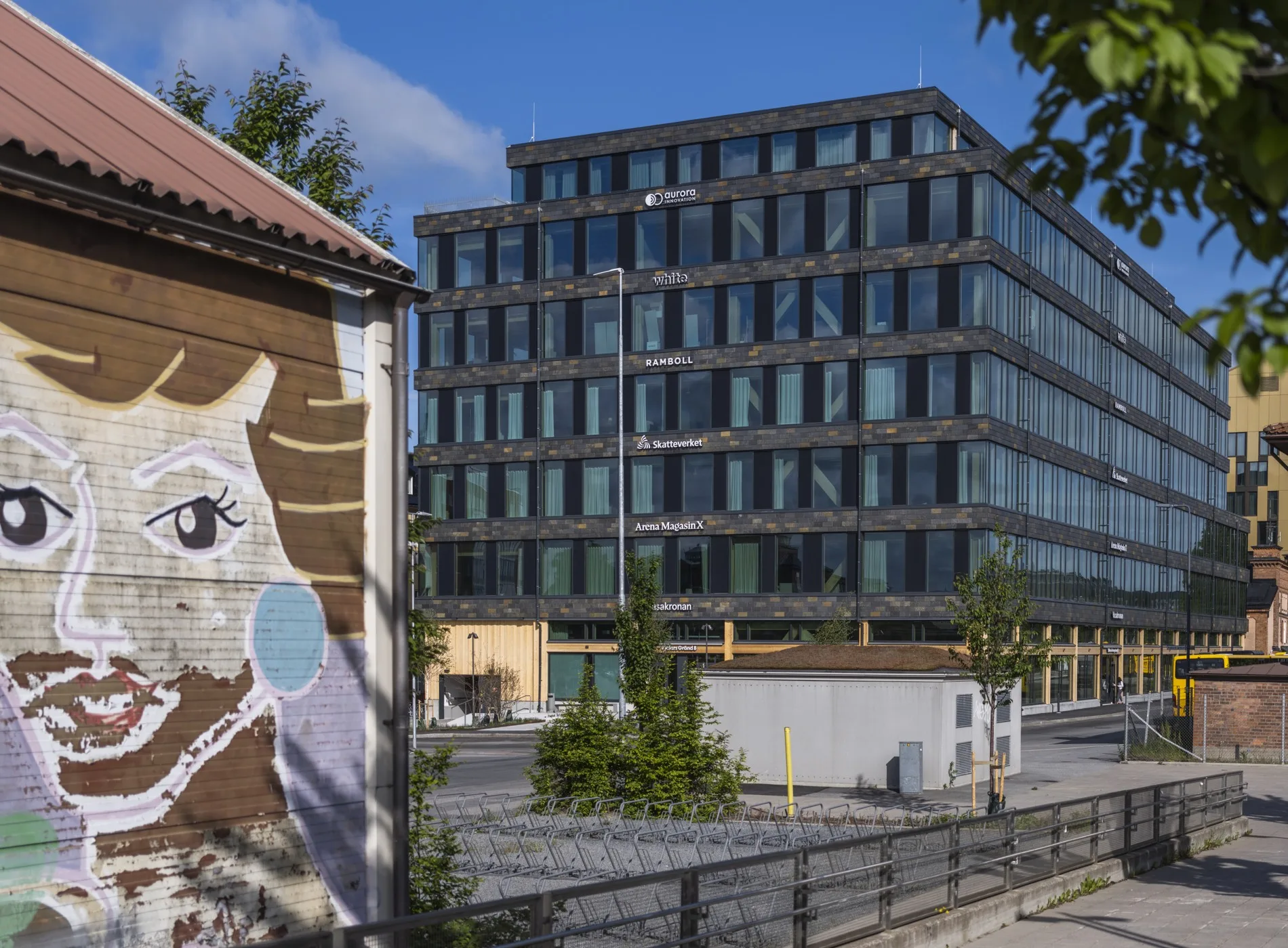 3. Ett modernt kontorshus med glasfasad bredvid en vägg med konstnärlig målning av en uggla.