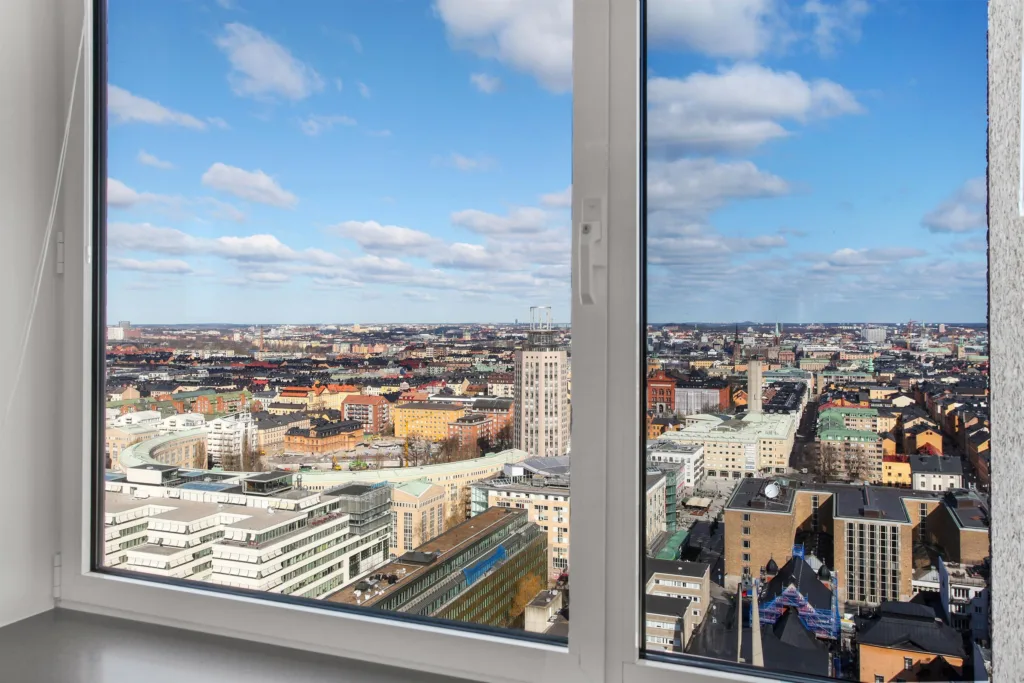 5. En vy över en stad med höga byggnader och blå himmel, sedd genom ett stort fönster.