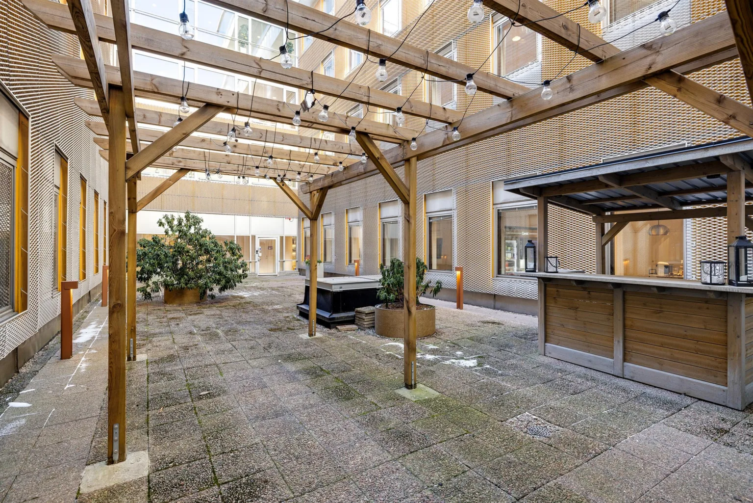 1. En innergård med träramverk, grönska och ett litet kaféområde.