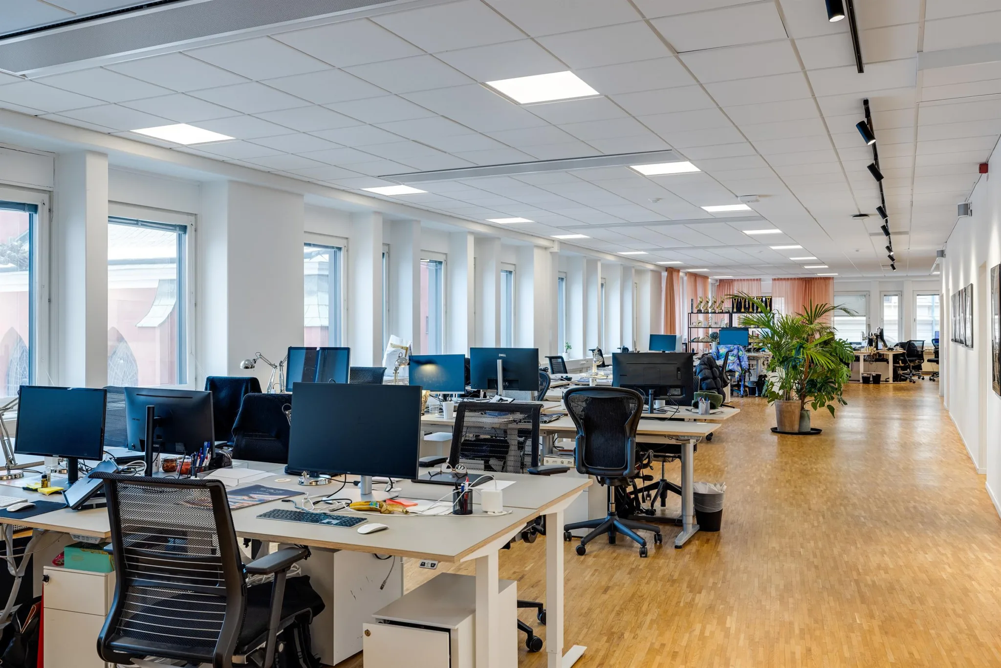 2. Ett öppet kontorslandskap med skrivbord, kontorsstolar och stora fönster.